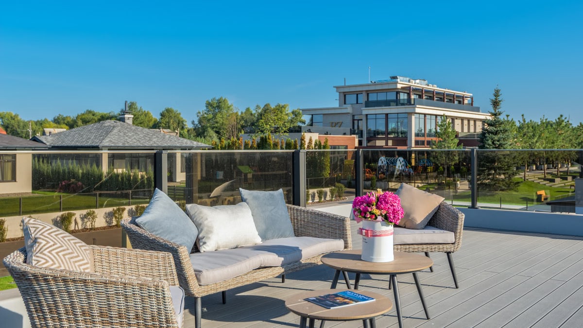 Outdoor terrace with seating and view of modern buildings under clear sky.